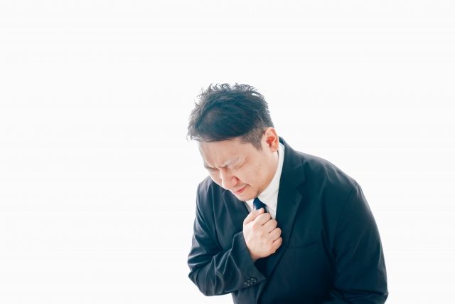 胸元を抑えるスーツを着た男性