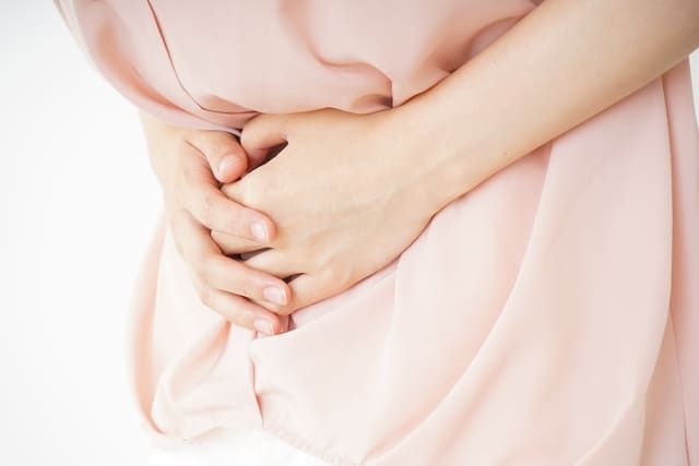 お腹を抑える女性